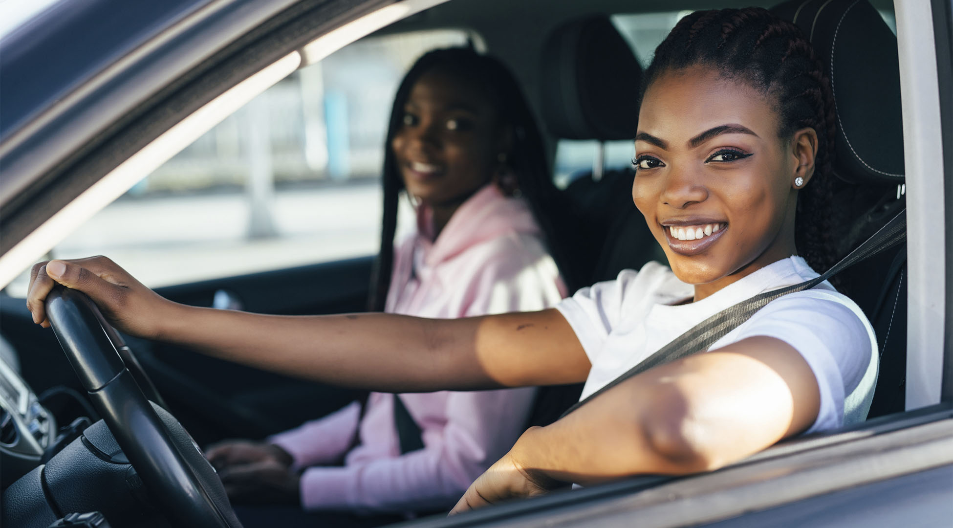 Mulher ao volante e outra ao seu lado no banco do passageiro