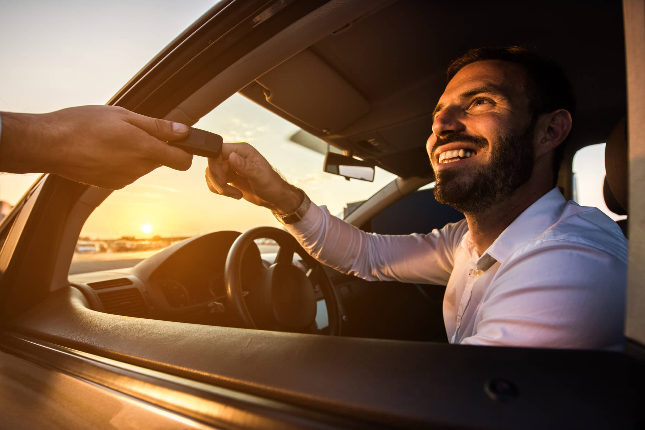 Homem ao volante enquanto recebe a chave do carro sorridente