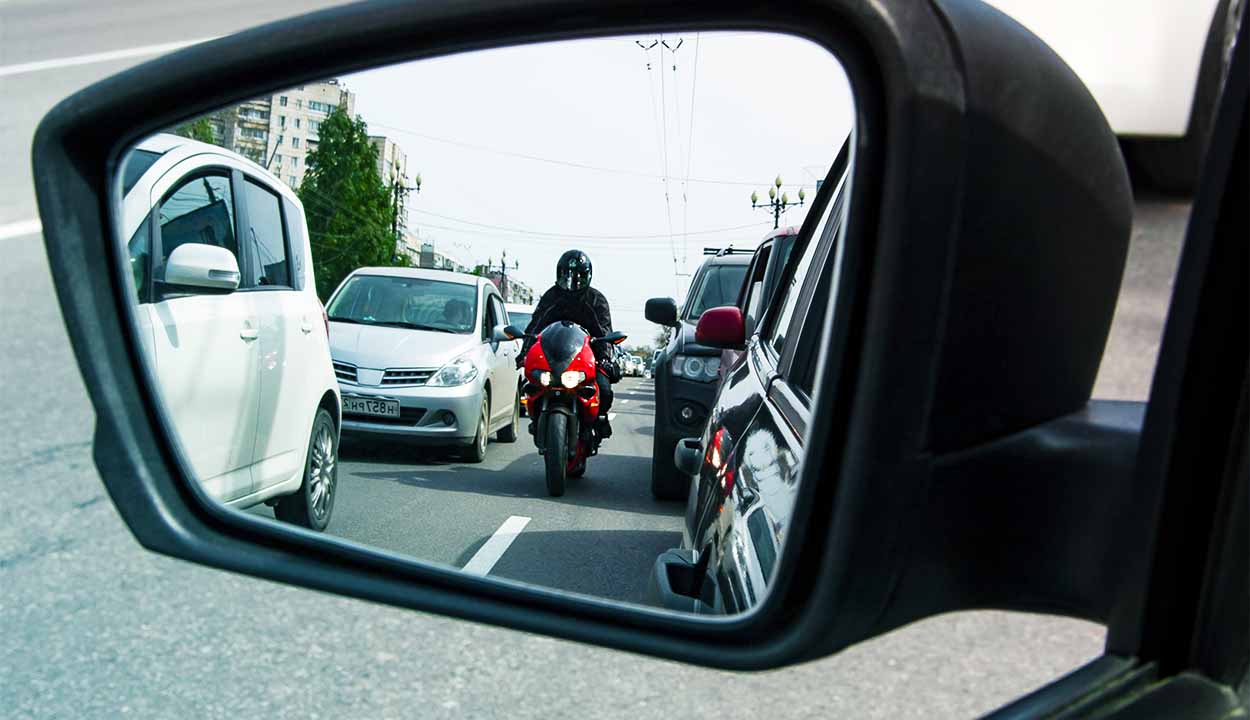 Retrovisor de carro mostrando um motoqueiro