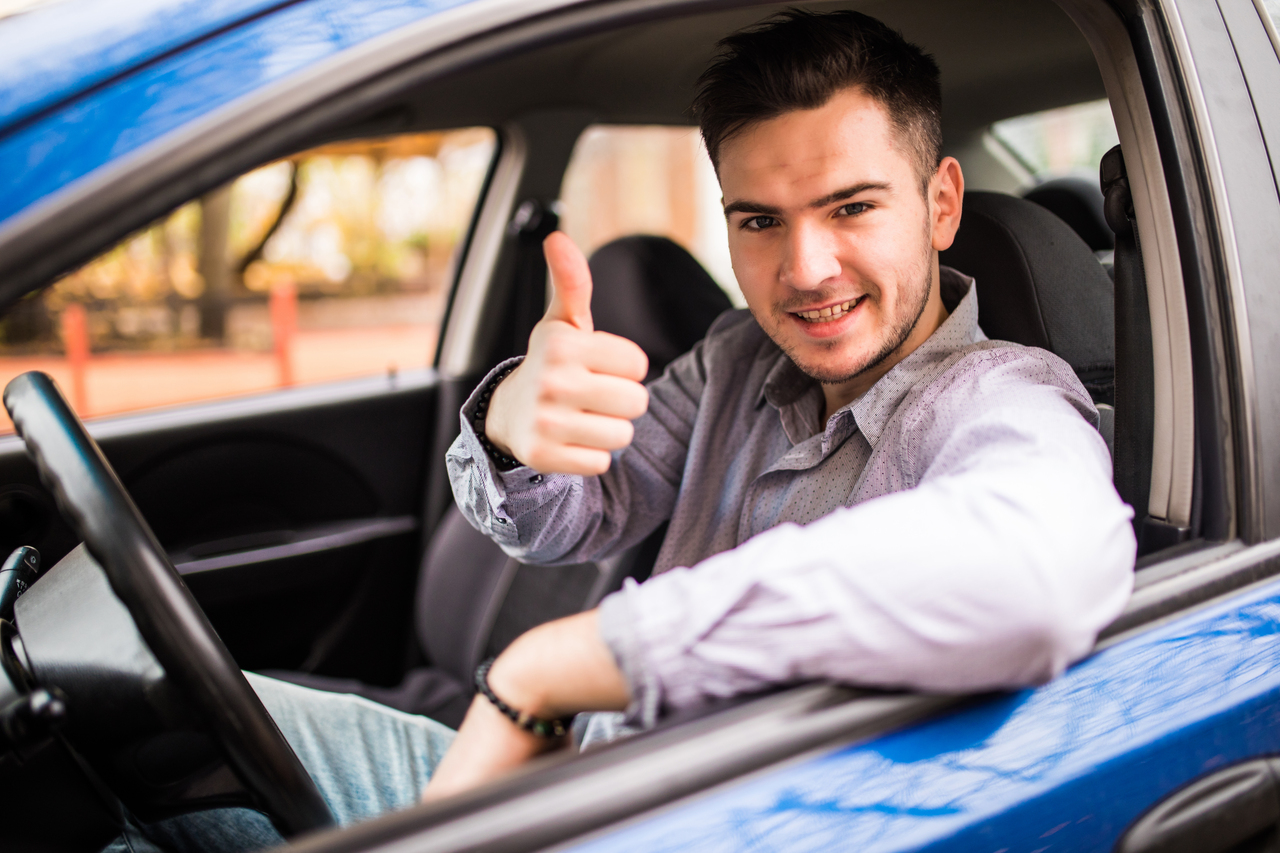 Homem faz sinal de positivo pela janela de seu carro